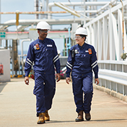 Two workers wearing PPE and walking through manufacturing plant in Singapore.