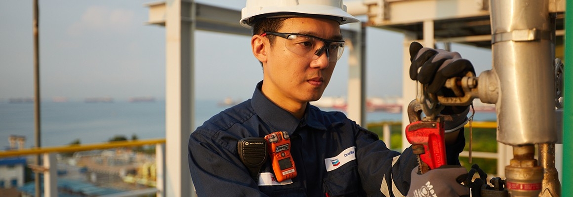 Worker using valve wrench at Oronite plant.